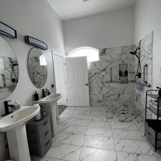 A modern bathroom with marble tiles, dual sinks, and large mirrors.