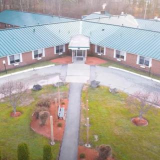 An aerial view of a building with a central entrance, surrounded by landscaped gardens.