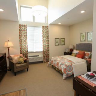 A cozy bedroom with a neatly made bed, armchair, and decorative elements.
