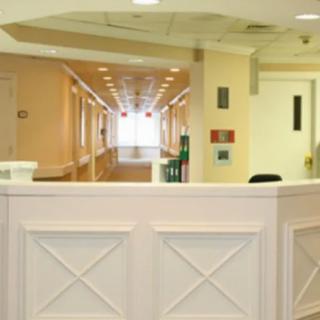 An empty hospital hallway with a reception desk in the foreground.