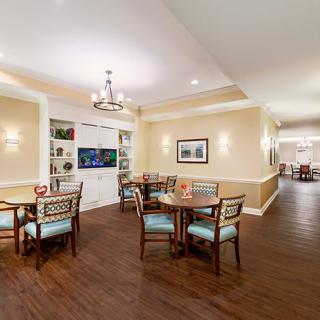 A cozy dining area with several tables and chairs, featuring elegant lighting and decor.