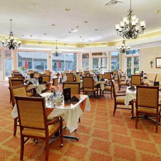 An elegant dining area with neatly arranged tables and chairs, adorned with chandeliers and large windows.