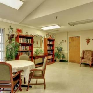 A cozy library reading room with bookshelves, a table, and comfortable chairs.