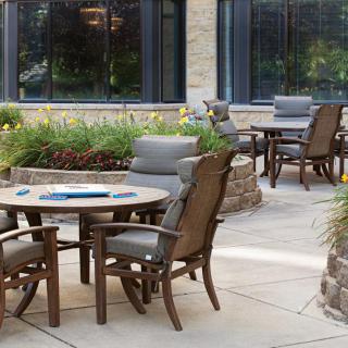 An outdoor patio setup with tables and chairs surrounded by lush garden landscaping.