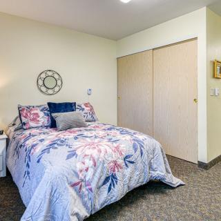 A neatly arranged bedroom with a floral bedspread and a closet.