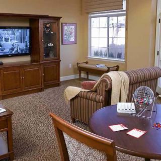 A cozy living room with a sofa, television, and table near a window.