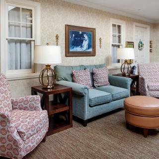 A cozy living room with a sofa, armchairs, and warm lighting.