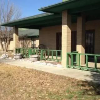 A view of a building with a green-railed porch and a yard.