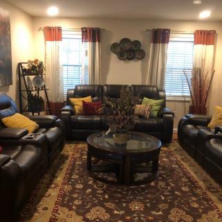 A cozy living room with leather sofas and colorful pillows, featuring a central coffee table and decorative elements.