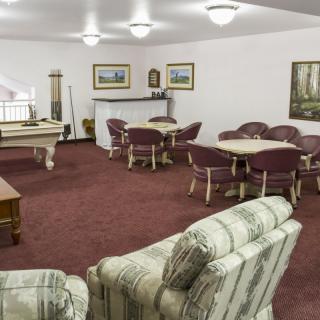 A cozy game room with a billiards table and ample seating.