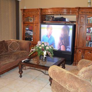A cozy living room with a large television, plush sofas, and a wooden entertainment center.