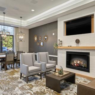 A modern living room with a fireplace and dining area, featuring comfortable seating and elegant lighting.
