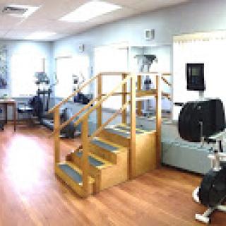 A physical therapy clinic featuring exercise equipment and a staircase for rehabilitation exercises.