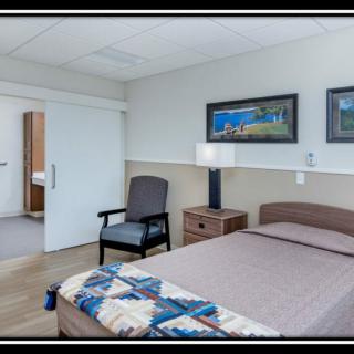A neatly arranged bedroom with a single bed, artwork on the wall, and essential furniture.