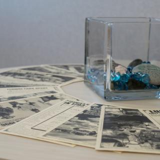 A decorative arrangement featuring vintage photographs spread out in a circle with a glass container filled with blue ornaments at the center.