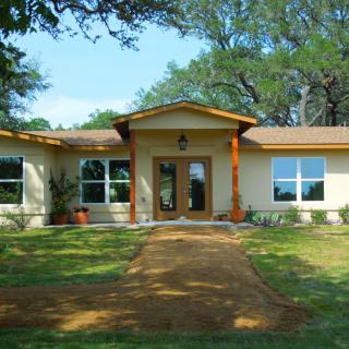 A single-story house with a front yard and surrounding trees.