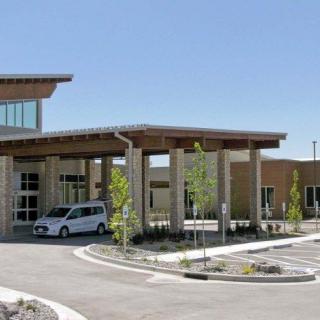 A modern building entrance with a car parked nearby on a sunny day.