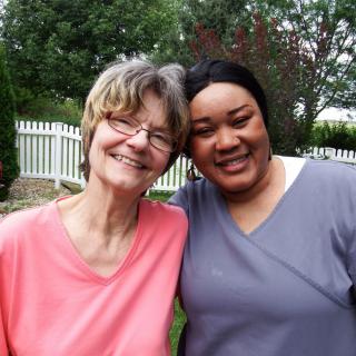 Two people smiling and posing together in a garden setting.