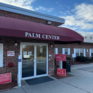 The entrance to the Palm Center, featuring a maroon awning and clear signage against a brick facade.