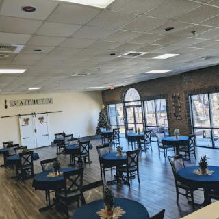 A spacious dining area with blue tables and large windows, creating a bright and inviting atmosphere.