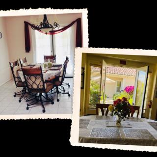 A cozy dining area with a table set, chairs, and floral decor in front of a bright window.