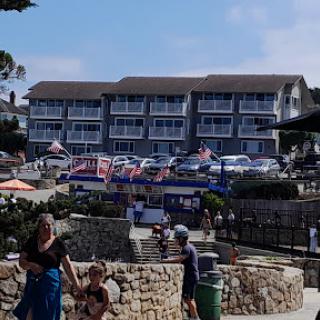 A sunny day at the beach with a family enjoying the outdoor atmosphere near a hotel adorned with flags.