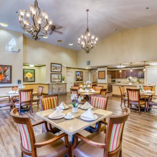 A well-decorated dining area with tables set for guests, featuring chandeliers and elegant furnishings.