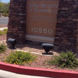 A stone sign with an address and plants in a landscaped area.