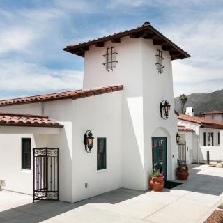 A Spanish-style building with white walls and red roof tiles under a clear blue sky.