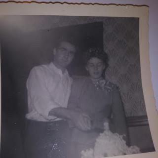 A vintage black and white photo capturing a couple celebrating with a cake.