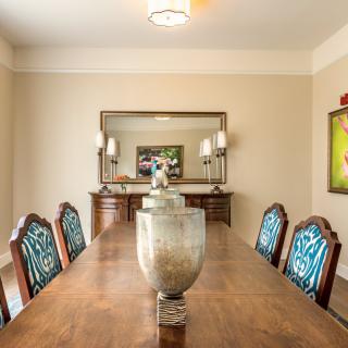 An elegant dining room with a long wooden table, patterned chairs, and decorative vases.