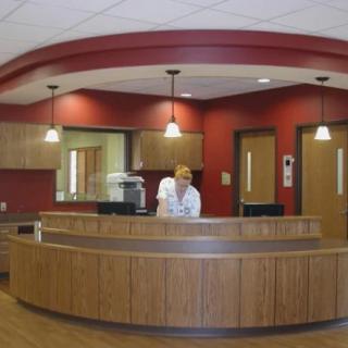 A modern reception desk with a person working behind it in an office setting.