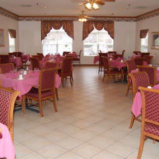 A spacious dining room with pink tablecloths and arranged seating.