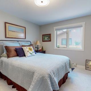 A cozy bedroom with a neatly made bed, decorative pillows, and wall art.