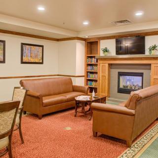 A cozy living room with leather sofas, a fireplace, and a bookshelf.