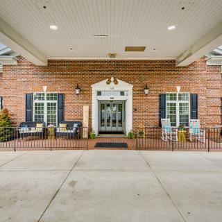 A welcoming brick entrance features outdoor seating and a covered porch.