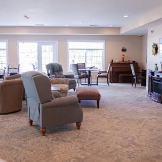 A spacious and well-lit living room with various seating options and a piano.