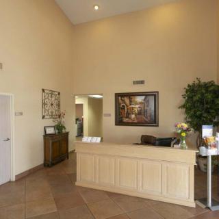 A spacious reception area with a desk, artwork, and plants.