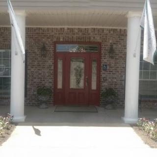A welcoming front entrance with a red door, brick walls, and white columns.