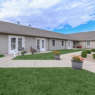 A well-maintained residential courtyard with green lawns and potted plants under a partly cloudy sky.