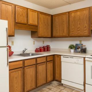 A cozy kitchen with wooden cabinets, a dishwasher, refrigerator, and well-organized countertop decor.