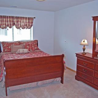 A cozy bedroom with a wooden bed and matching dresser.