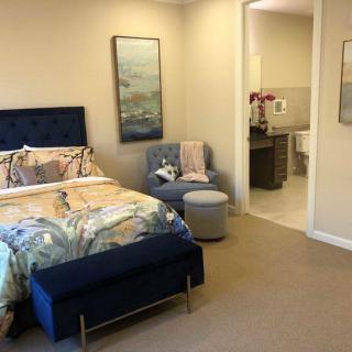 A modern bedroom with a comfortable bed, stylish armchair, and a view into the bathroom.