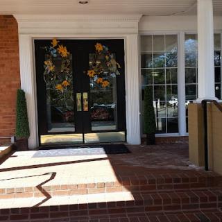 A building entrance featuring double glass doors with decorative designs and a brick pathway.