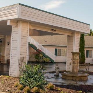 The entrance of a motel featuring a small fountain and landscaped area.