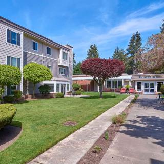A residential apartment complex with well-maintained lawns and trees under a clear blue sky.