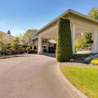 A serene entrance to a building surrounded by lush landscaping.