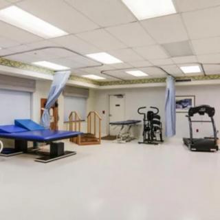 A well-equipped rehabilitation room featuring various exercise machines and therapy tables.