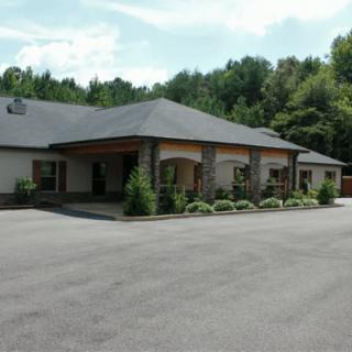 A residential building with a landscaped driveway and surrounding trees.