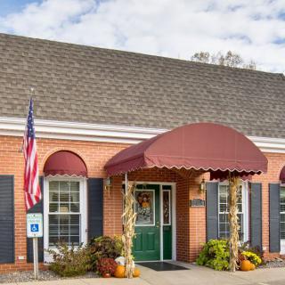 A brick building with a red awning and an American flag, adorned with seasonal decorations at the entrance.